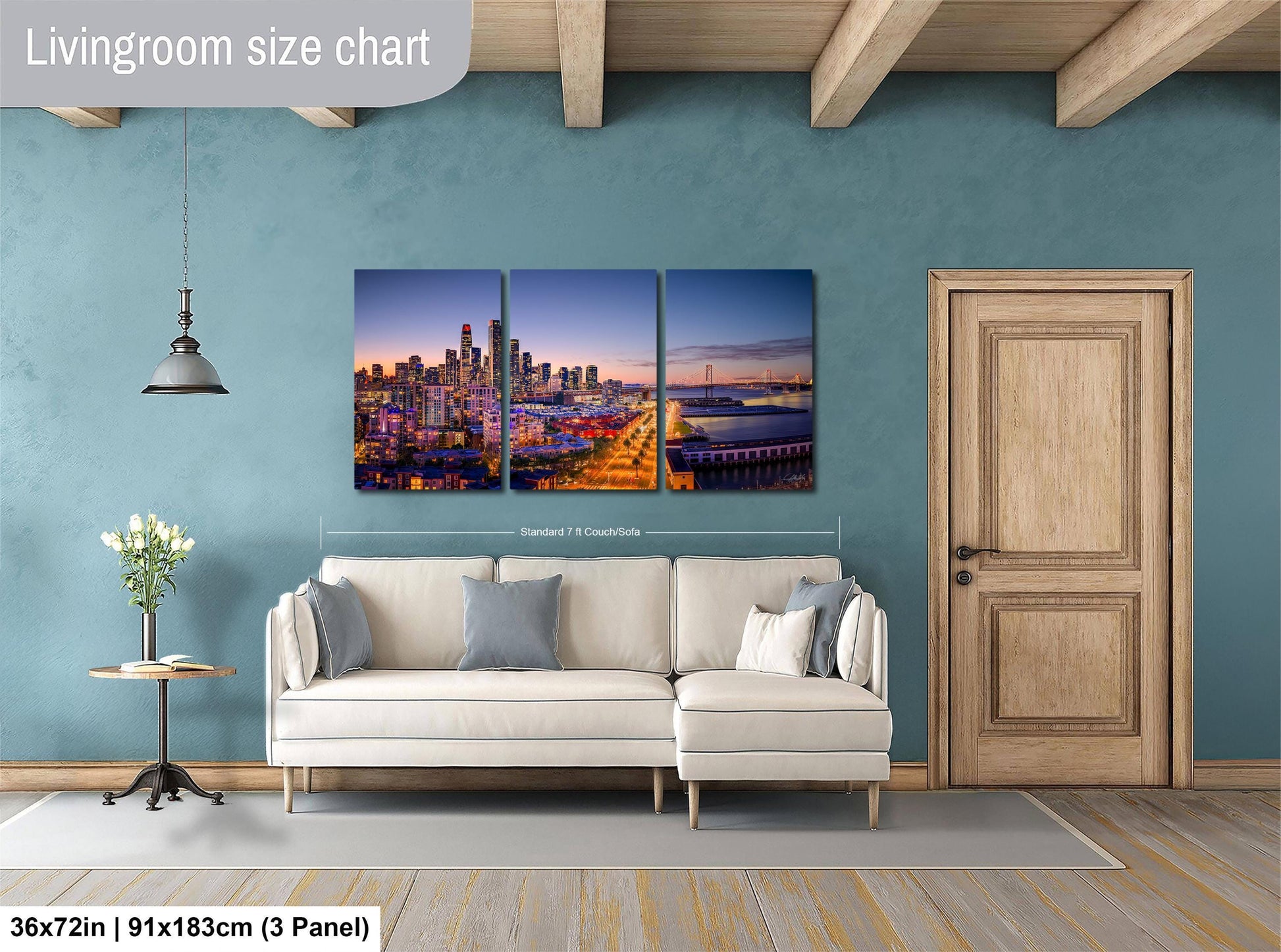 The image is a living room with a large wall art depicting a city skyline at sunset. The wall art is a collage of three panels, each showing a different part of the cityscape. The living room has a white sofa and a wooden door, and the floor is covered with a gray rug.