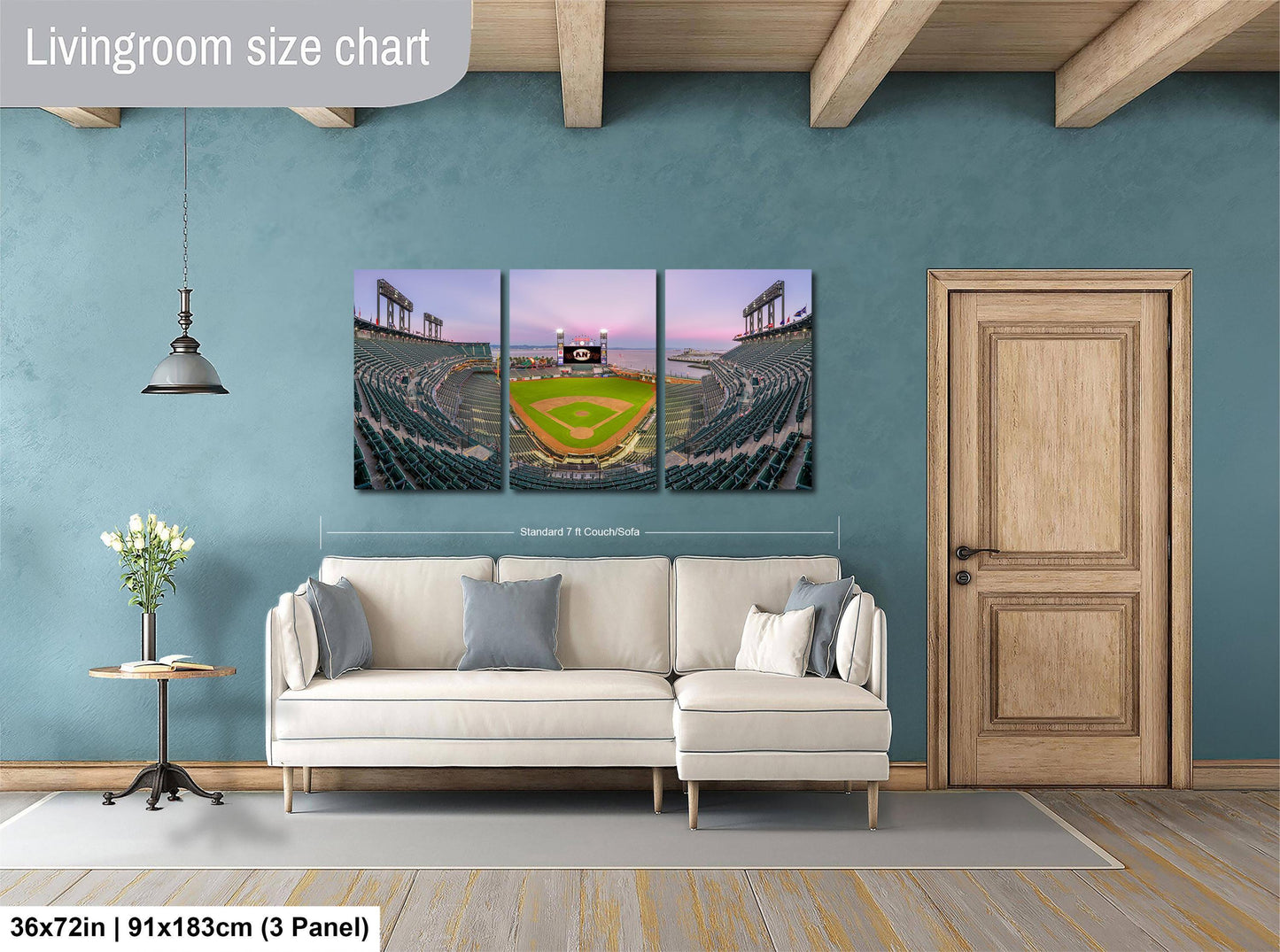 The image is a living room with a large wall art depicting a baseball stadium. The wall art is a collage of three panels, each showing different aspects of the stadium, including the field, seating, and the sky. The living room has a white sofa and a wooden door, creating a cozy and inviting atmosphere.
