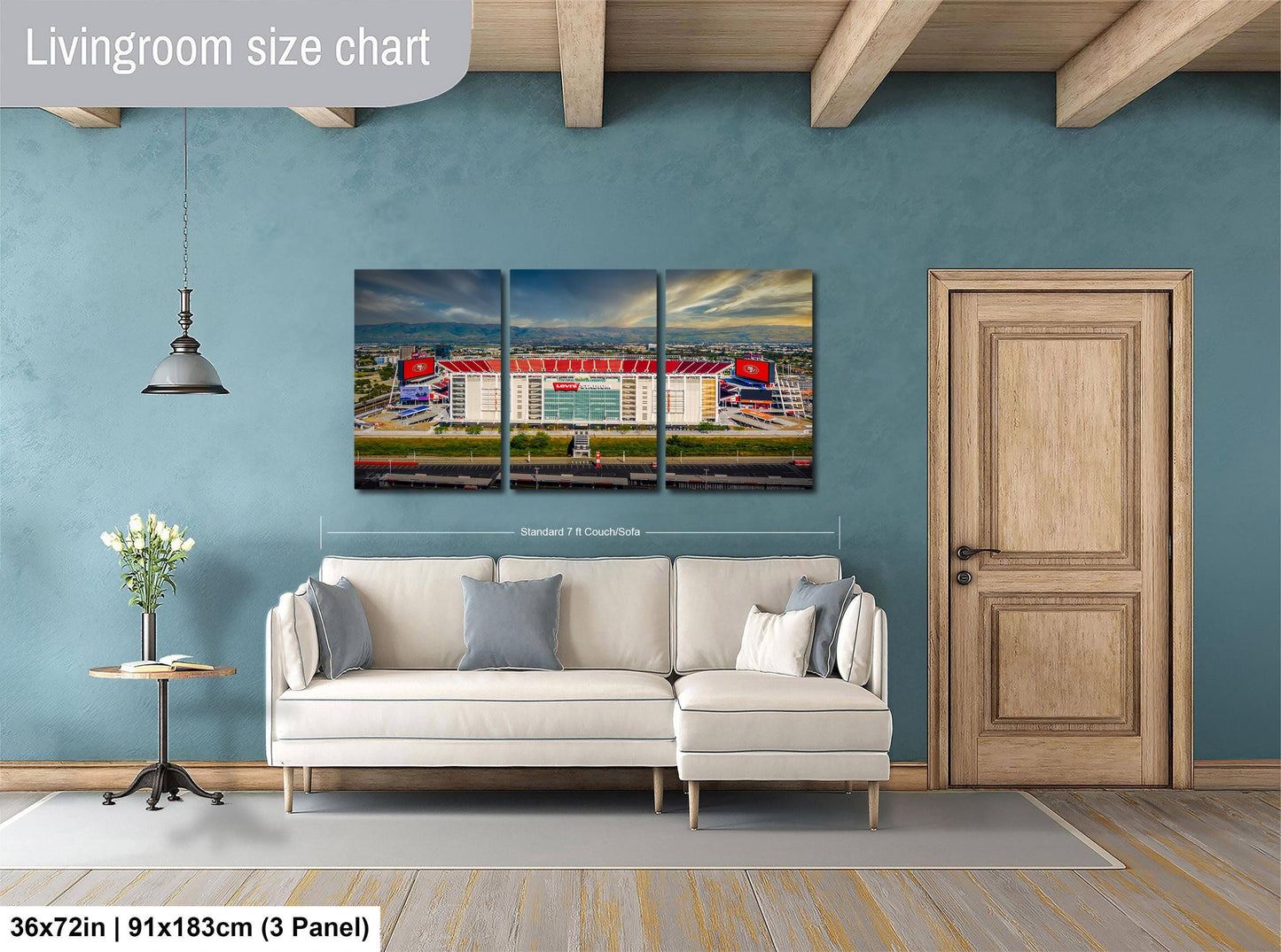 The image is a living room with a large wall art depicting a stadium. The wall art is a collage of three panels, each showing different aspects of the stadium. The living room has a white sofa and a wooden door, and there is a potted plant and a vase on a table. The wall art is approximately 36 inches wide and 9 inches tall, and it is mounted on a blue wall.