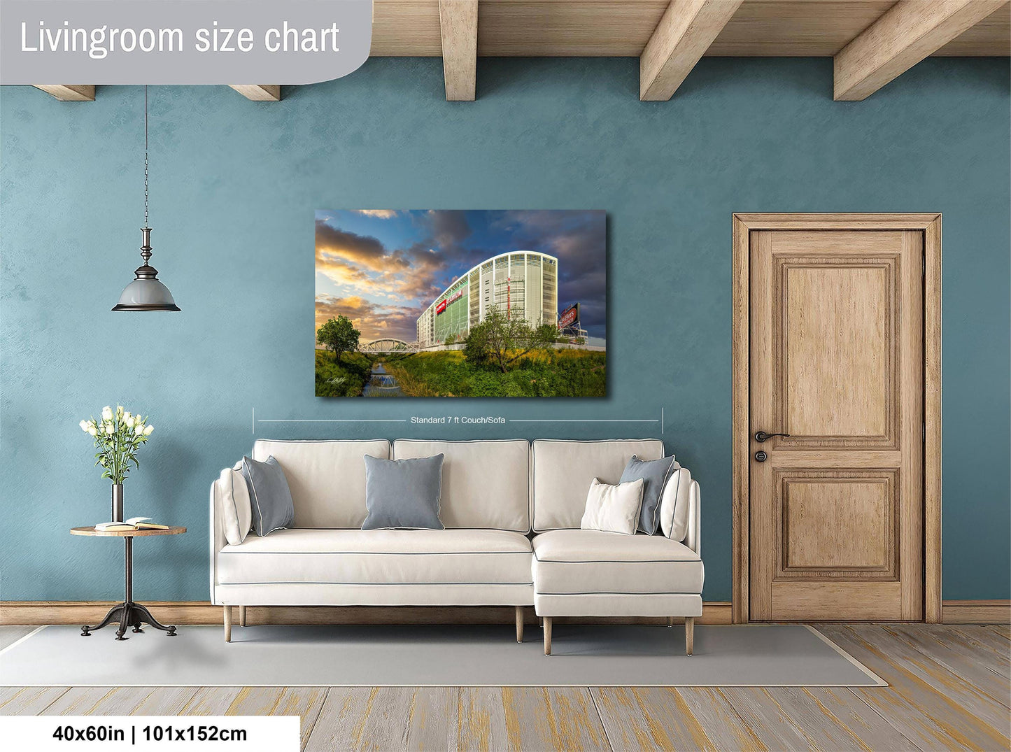 a living room with a large white sofa, a wooden door, and a painting of a building on the wall.