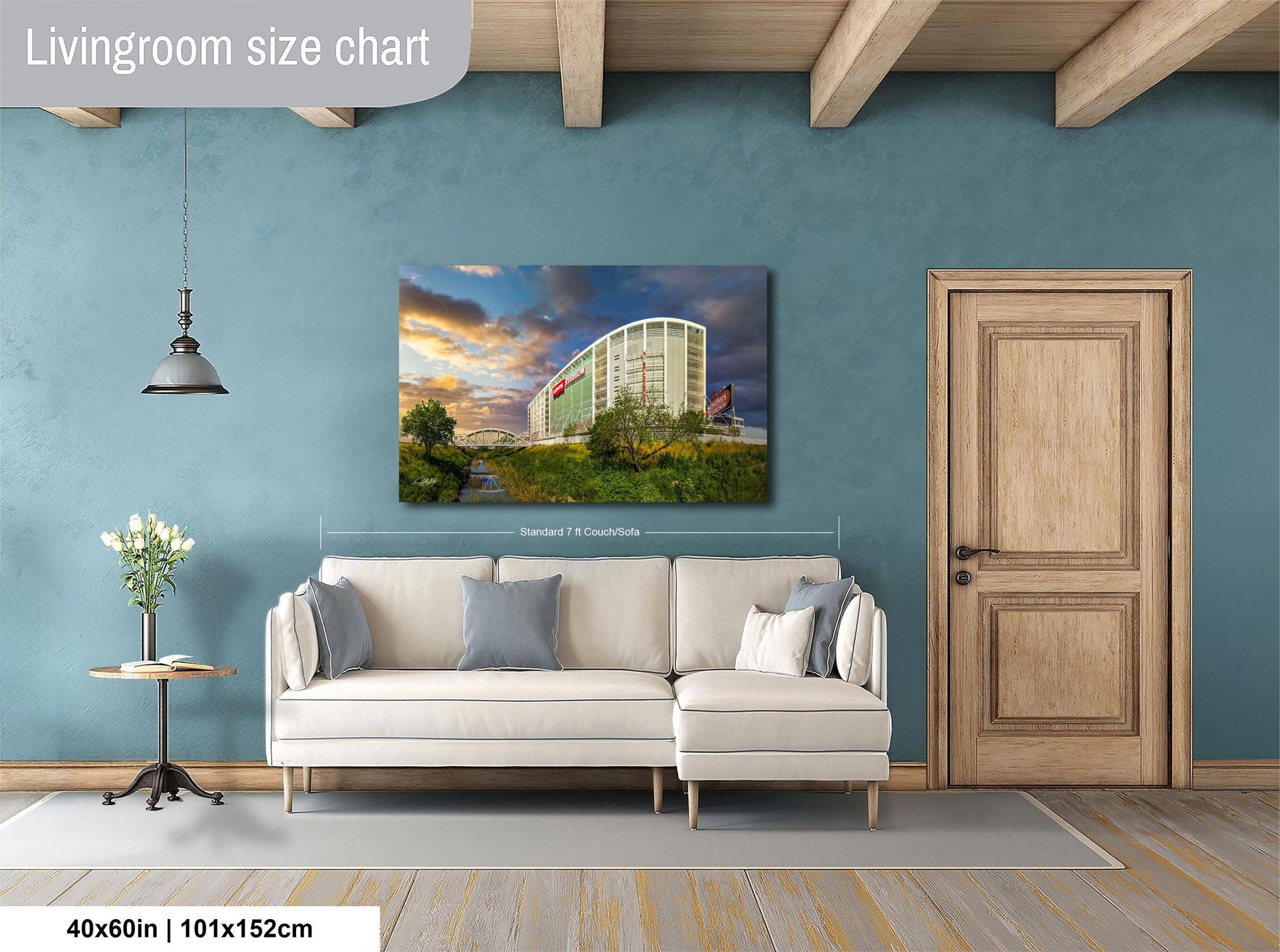 a living room with a large white sofa, a wooden door, and a painting of a building on the wall.