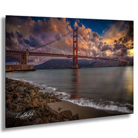 a stunning view of the Golden Gate Bridge at sunset, with its iconic red towers and suspension cables standing tall against a dramatic sky filled with clouds and vibrant colors.
