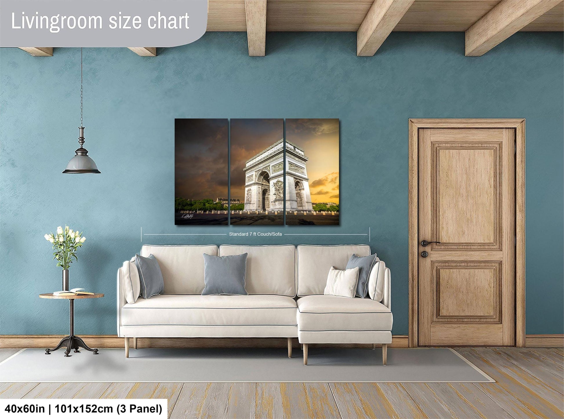 The image is a living room with a large white sofa, a wooden door, and a painting of the Arc de Triomphe hanging on the wall.