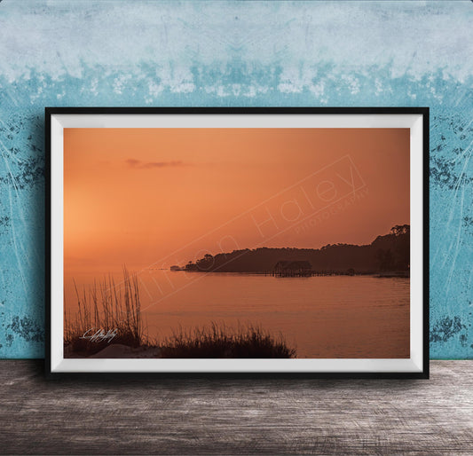 a serene sunset over a body of water, with a small island visible in the distance.