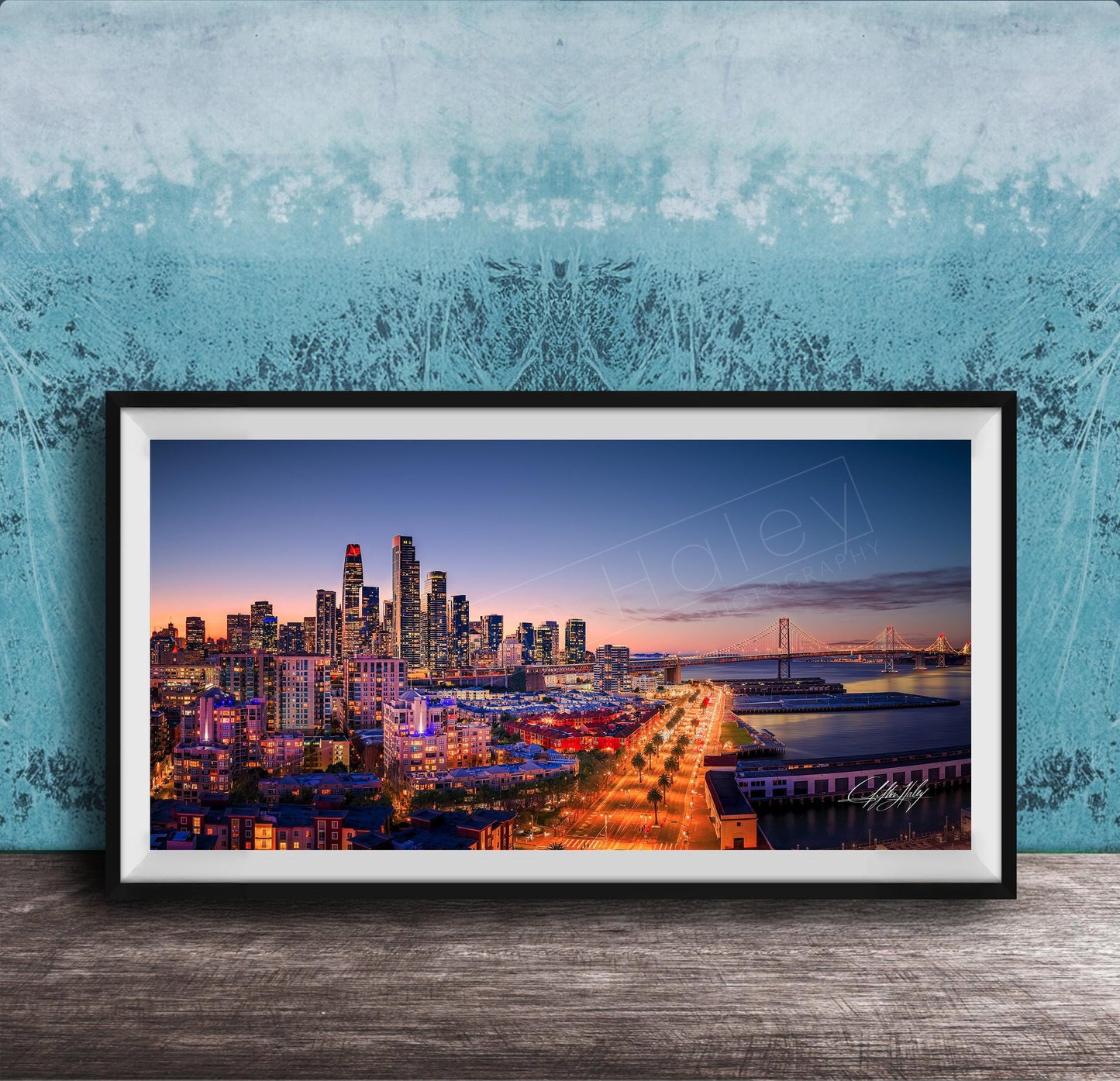 A framed photograph of a city skyline at dusk, with the city lights illuminating the buildings and the water in the background.