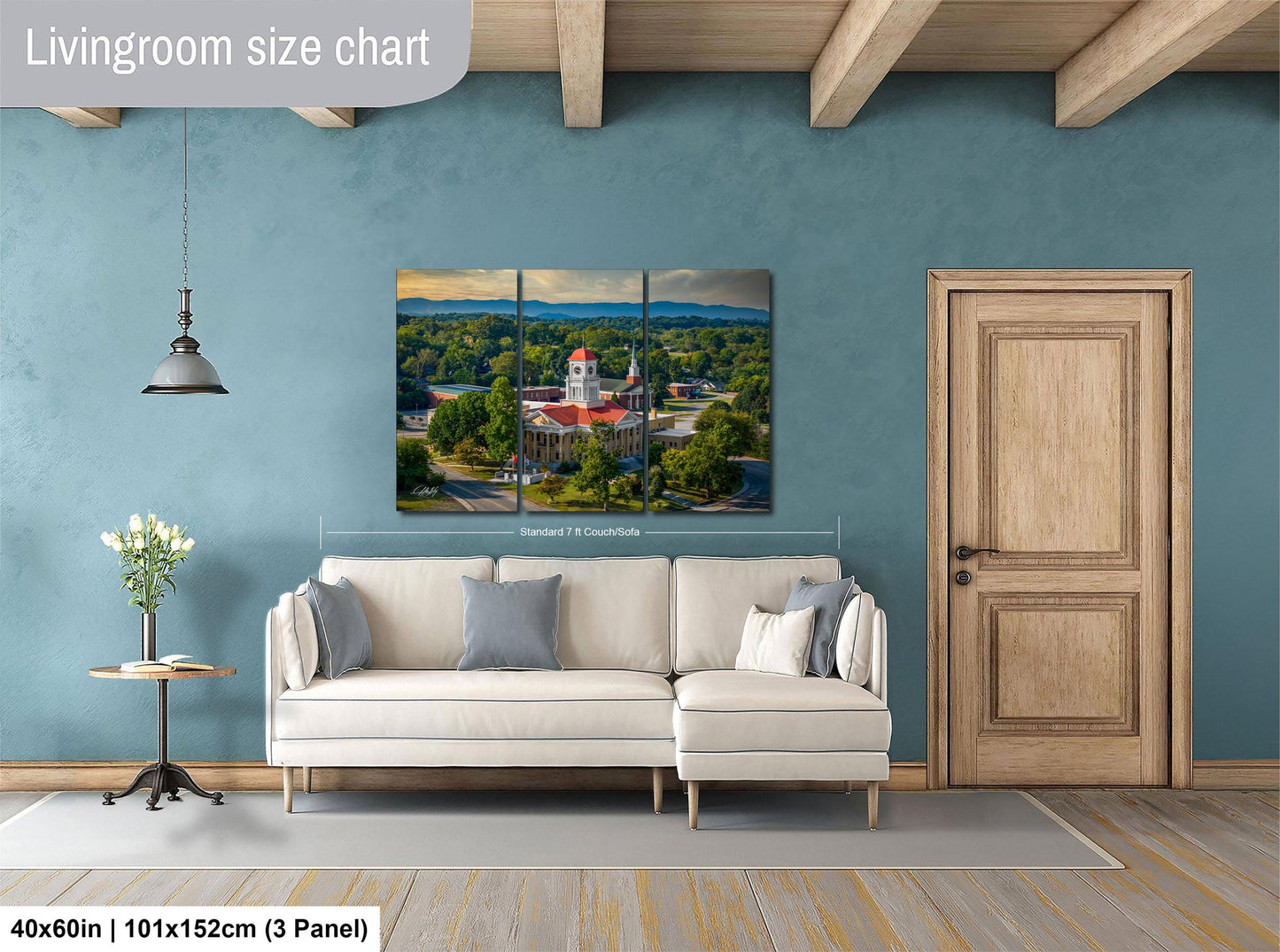The image is a living room with a large white sofa, a wooden door, and a painting of a building on the wall.