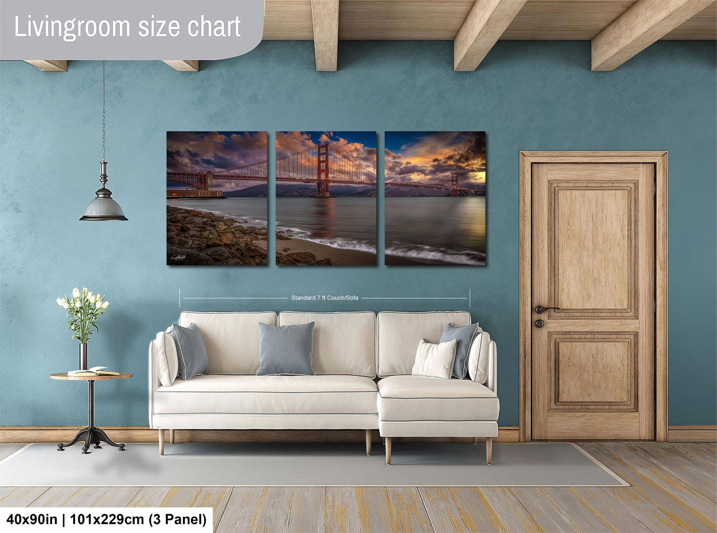 The image is a living room with a large wall-mounted painting depicting the Golden Gate Bridge at sunset. The painting is divided into three panels, each showcasing different aspects of the bridge and the surrounding landscape. The room has a white sofa and a wooden door, creating a cozy and inviting atmosphere.