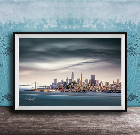 A framed photograph of the San Francisco skyline at sunset, with the Golden Gate Bridge and other iconic structures visible in the distance.