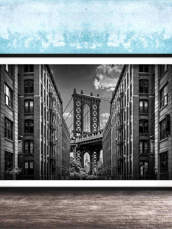 A black and white photograph of the Manhattan Bridge in New York City, with the bridge's intricate steel truss structure and the surrounding tall buildings in the background.
