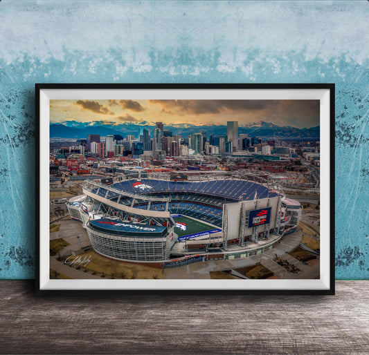 The image is an aerial view of a large sports stadium, likely a football stadium, with the city skyline in the background.