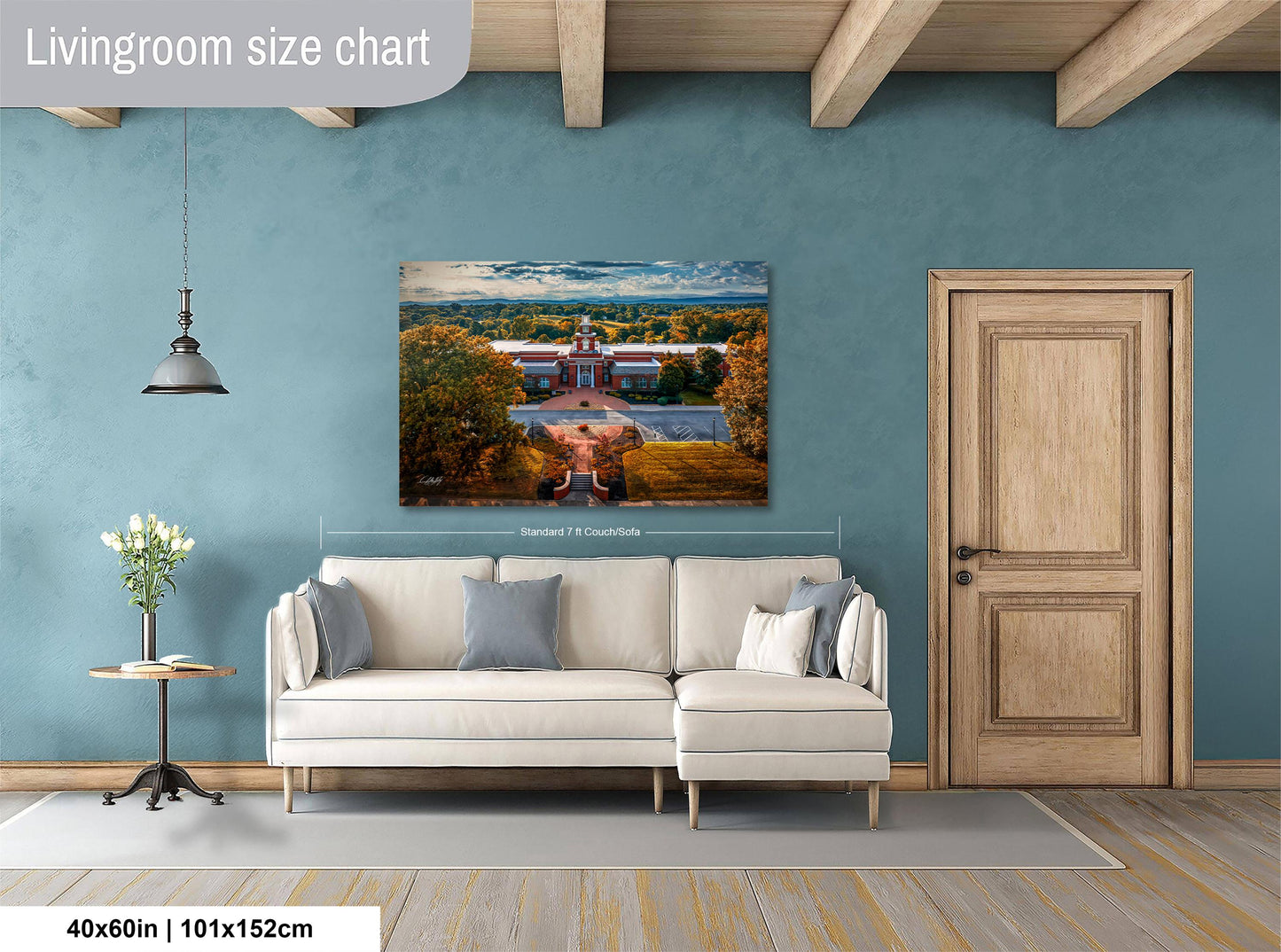 a living room with a large painting of a building on the wall, a white sofa, a wooden door, and a small table with a vase of flowers.