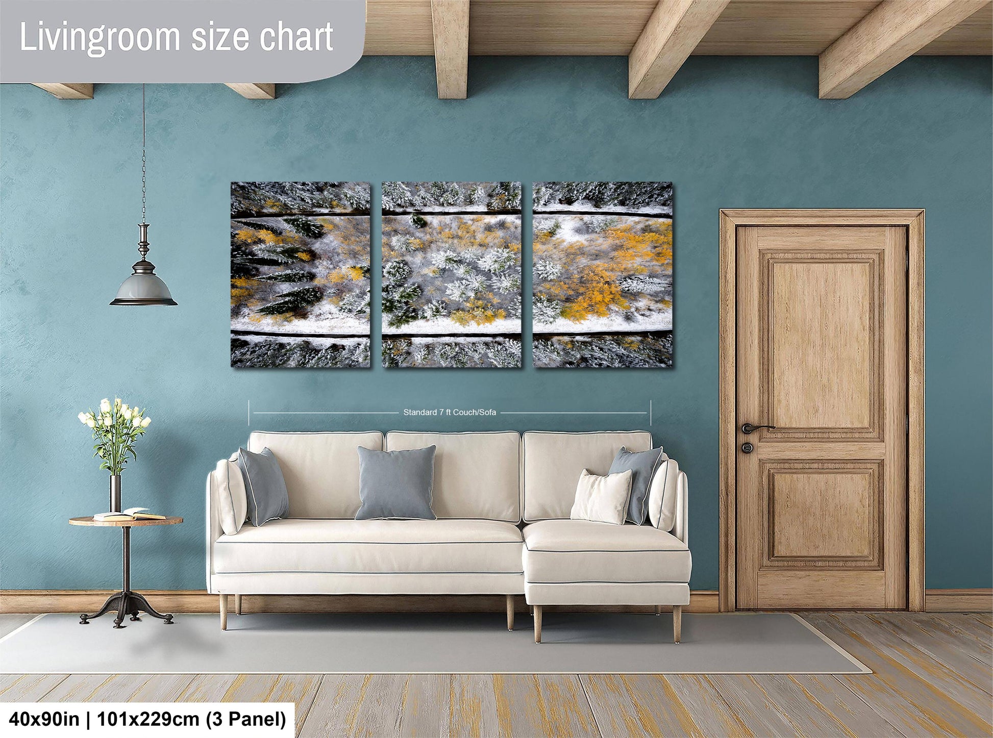 The image is a living room with a large, three-panel landscape painting hanging on the wall. The painting depicts a snowy scene with trees covered in snow. The room has a white sofa and a wooden door, creating a cozy and inviting atmosphere.