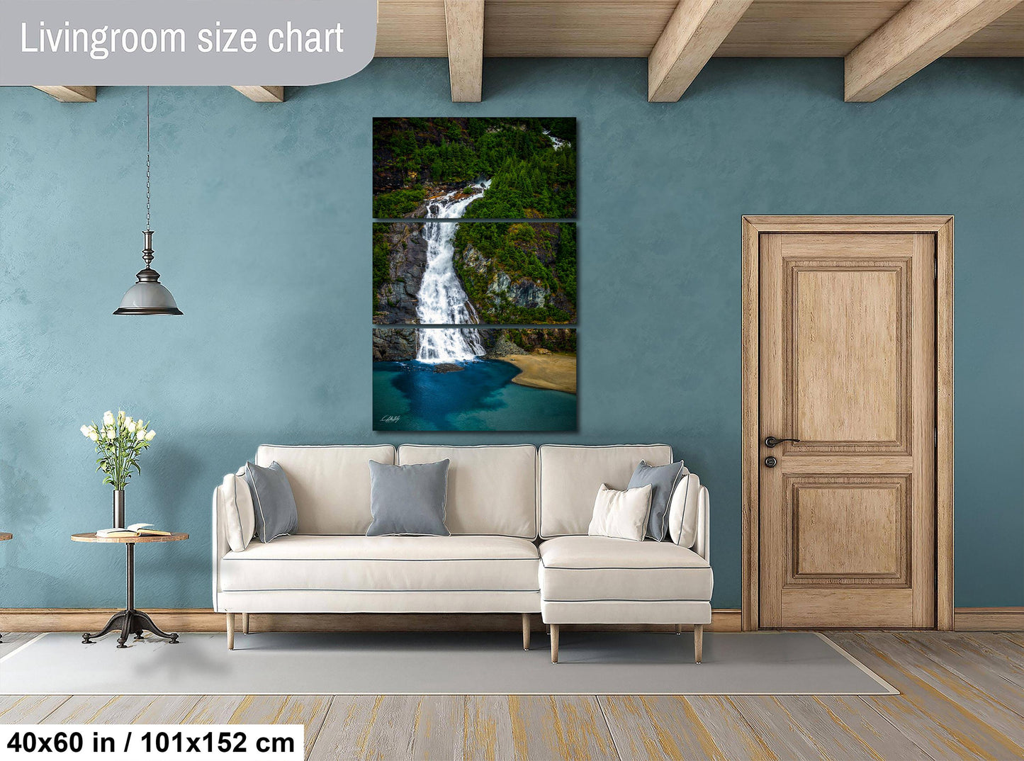 The image is a living room with a large white sofa, a wooden door, and a painting of a waterfall on the wall.