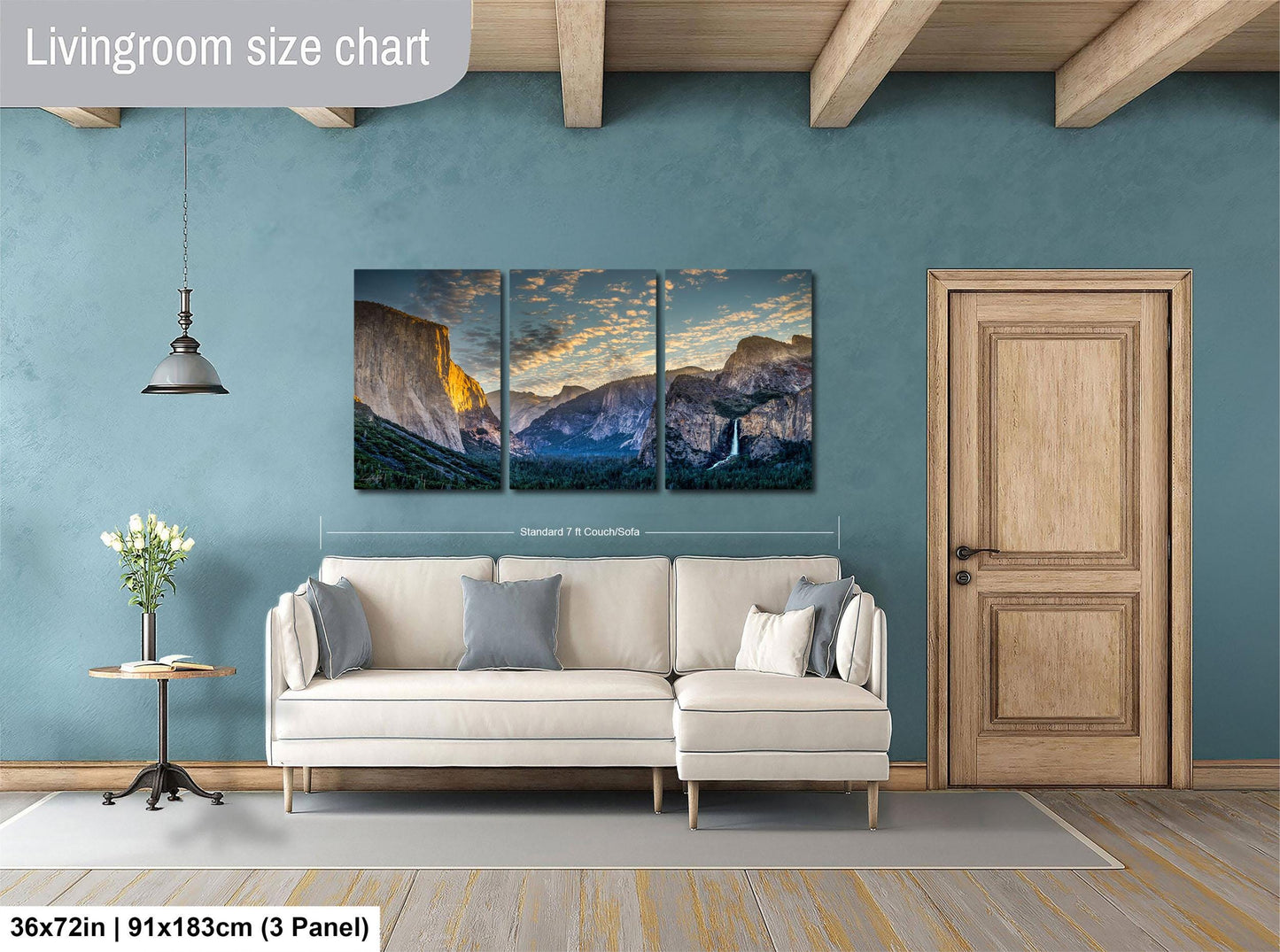 The image is a living room with a large, three-panel landscape painting hanging on the wall. The painting depicts a scenic mountain range with a sunset in the background. The room has a white sofa and a wooden door, creating a cozy and inviting atmosphere.