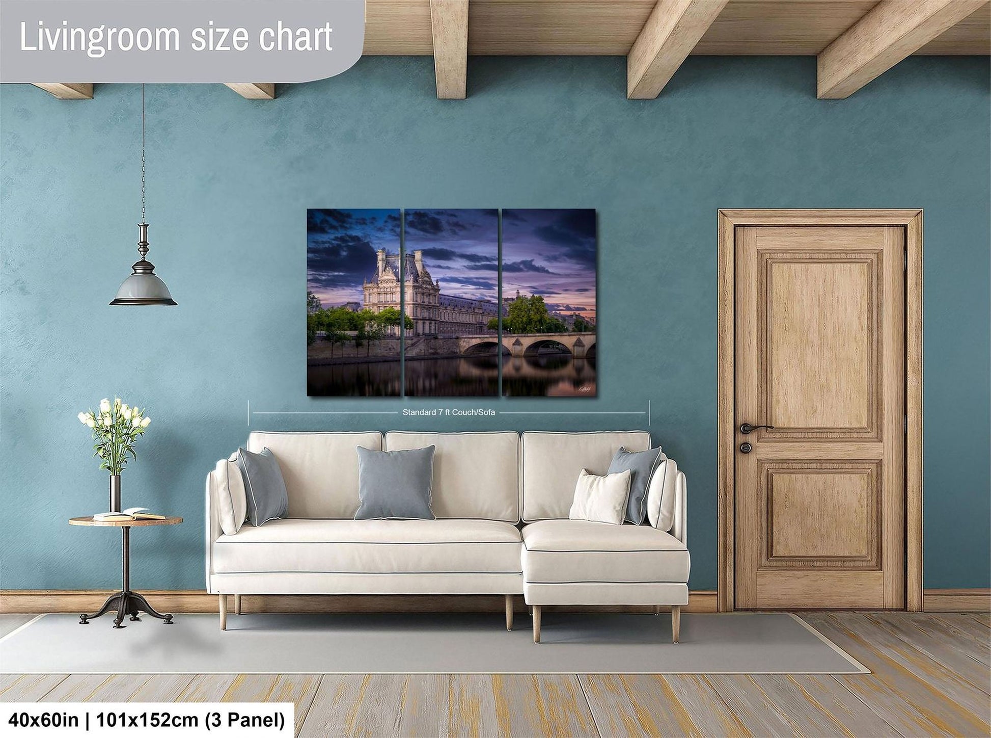 The image is a living room with a large white sofa, a wooden door, and a painting of a castle on the wall.