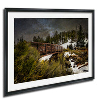 A wooden bridge spans a snowy mountain landscape under a starry night sky.