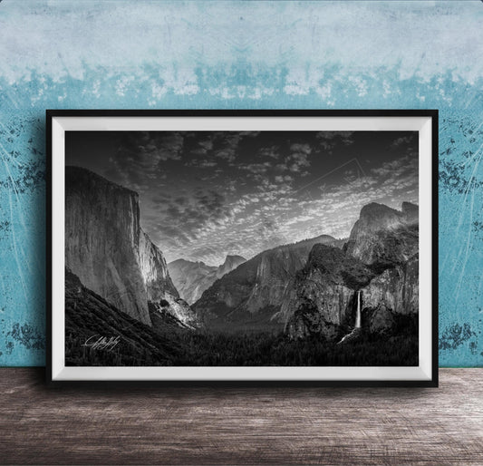 A framed black and white photograph of a mountainous landscape, with a waterfall visible in the distance.