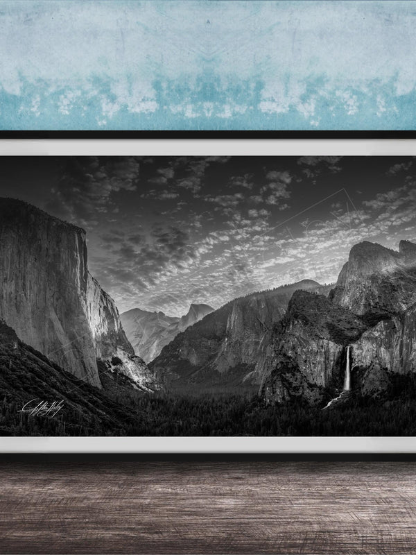 A framed black and white photograph of a mountainous landscape, with a waterfall visible in the distance.