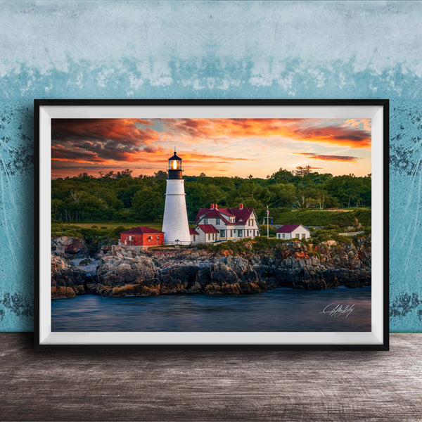 A framed photograph of a lighthouse on a rocky shore, with a colorful sunset sky in the background.