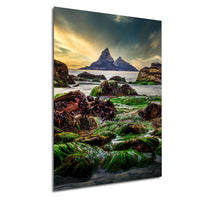 a serene coastal landscape with a rocky shoreline, lush green vegetation, and a distant mountain range under a dramatic sky.